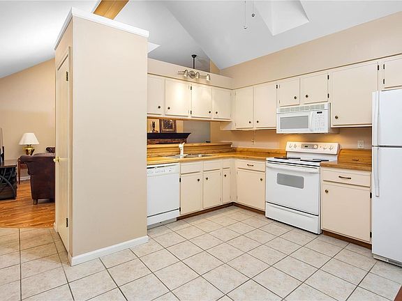Kitchen with vaulted ceiling, skylight, ceramic tile flooring & breakfast bar.