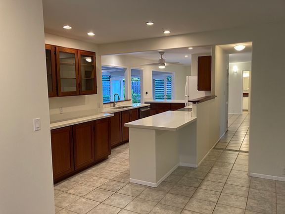 Kitchen view from front door. Hallway to the right goes to 3 bedrooms. Light at the end of the hall is the shared bathroom that has an entrance from inside and poolside.
