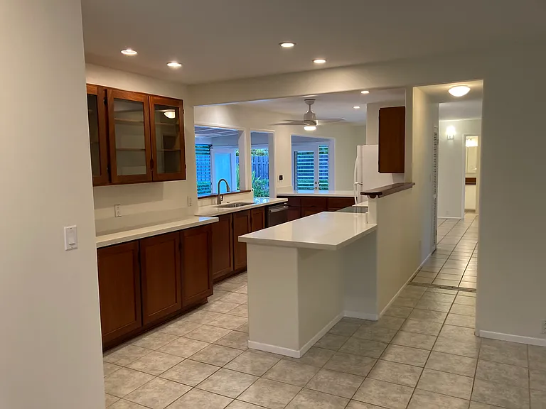 Kitchen view from front door. Hallway to the right goes to 3 bedrooms. Light at the end of the hall is the shared bathroom that has an entrance from inside and poolside.