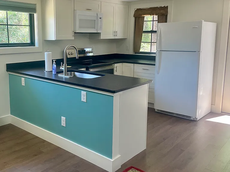 Kitchen with electric stove and small dishwasher.