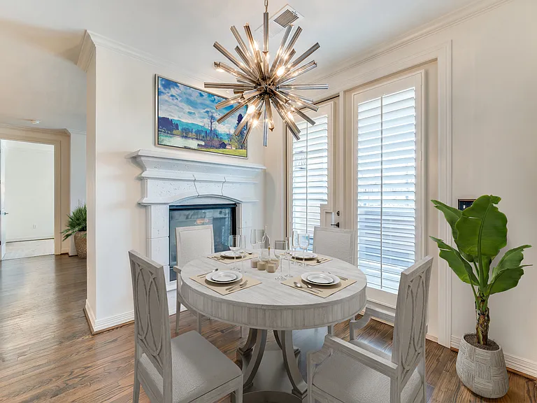 Virtually Staged Dining Area with Double Sided Fireplace. Neighboring Covered Balcony Beyond French Doors.