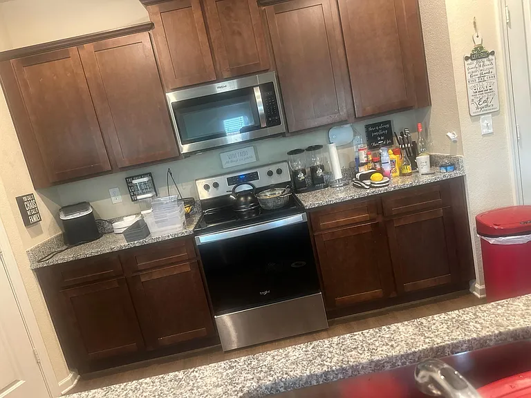 Galley-style kitchen with ample wood cabinetry, granite-look counters, and a full stainless-steel appliance package.