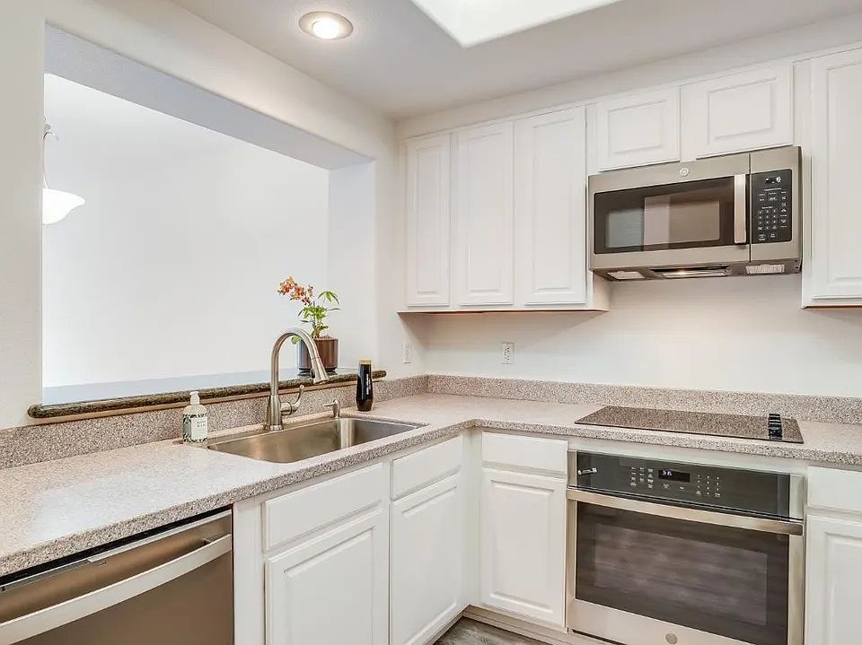 Spacious kitchen equipped with a microwave, oven, refrigerator, and dishwasher, plus abundant cabinet storage and generous counter space.