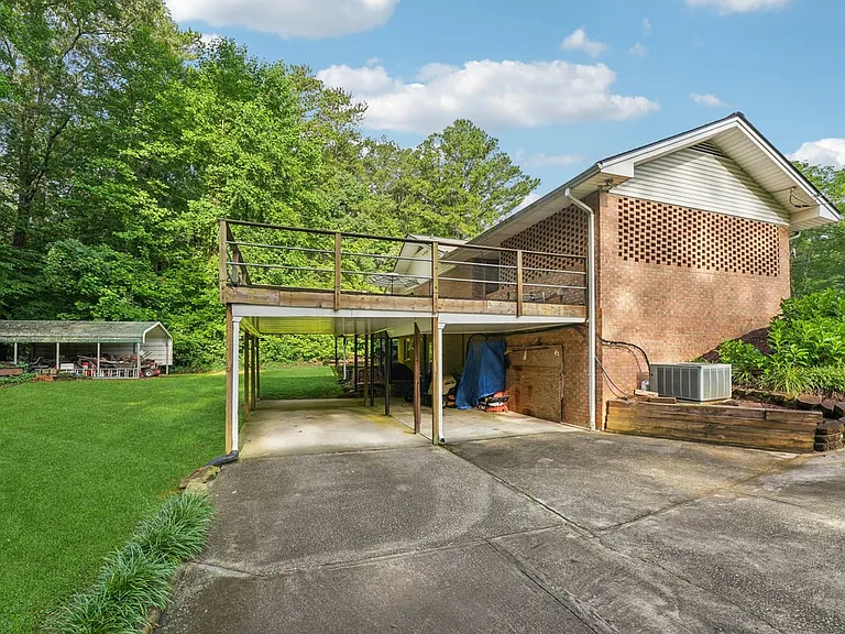 A functional covered patio space where convenience meets nature, offering protected storage, open concrete flooring, and easy access to the peaceful backyard setting.
