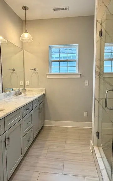 Primary bathroom with dual vanities and walk in shower