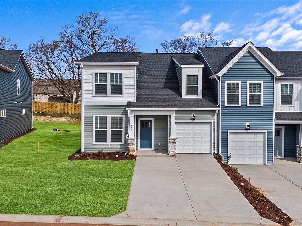 Townhome exterior with blue and white vinyl, stone columns, garage, and two car parking pad at Aspen