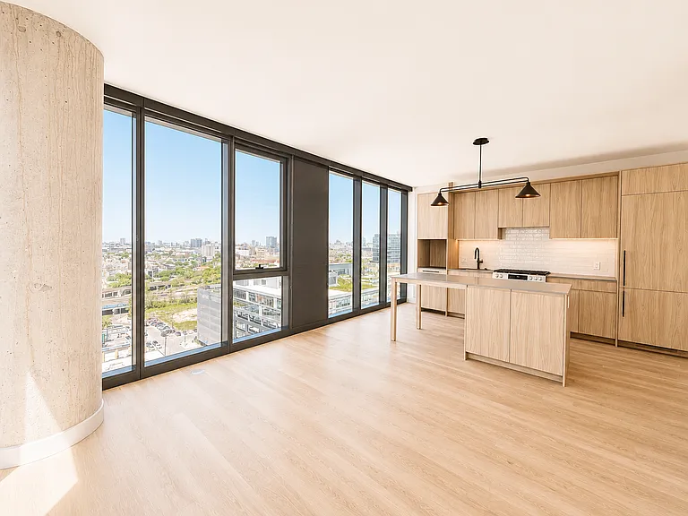Spacious open-concept living and kitchen at Stead 220 in Fulton Market, with a center island, floor-to-ceiling wraparound windows, and panoramic Chicago skyline views.