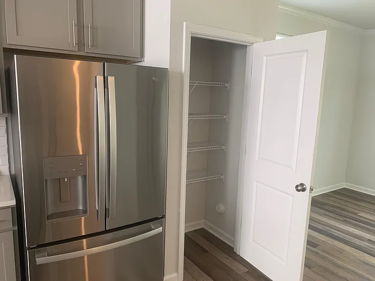 Brand new refrigerator next to pantry.