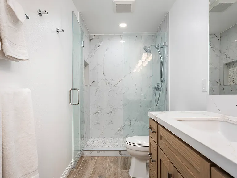 Newly remodeled primary bathroom, including custom cabinetry, 30" knee-hole vanity, large-scale porcelain tile walk-in shower and luxury Hansgrohe shower system.