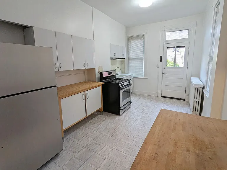 1st floor Kitchen with wonderful light, featuring refurbished vintage metal cupboards (upper section), as well as 2 spacious IKEA storage units w/wooden, butcher block counter tops, gas stove, refrigerator, the door leads to the garden