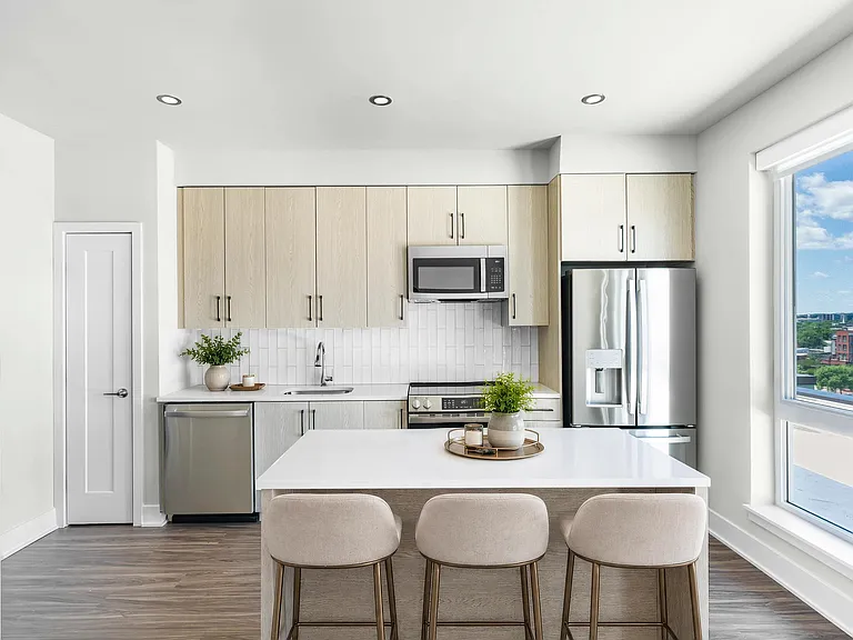 Bright kitchen with full-height cabinetry, quartz island seating, and large windows that bring in daylight and frame neighborhood views.