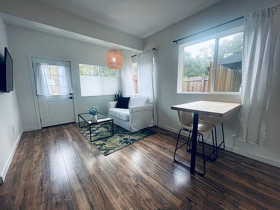 Living space has a white loveseat, coffee table and flat screen TV. Butcher block counter peninsula serves as dining space or computer workspace as needed.
