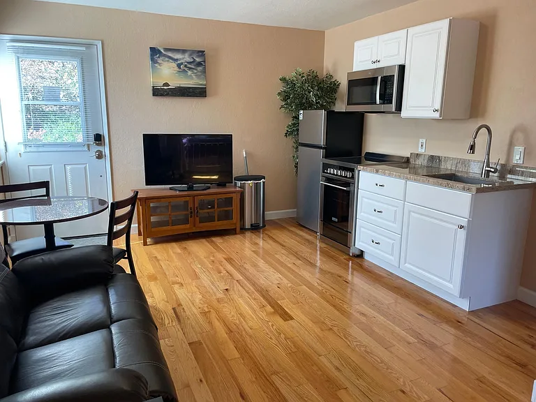 Newly installed kitchen area with granite counter top, electric stove and range, microwave and refrigerator.