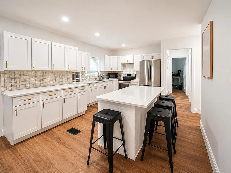 Spacious kitchen with large island seating, ample white cabinetry, and stainless-steel appliances for easy daily cooking.
