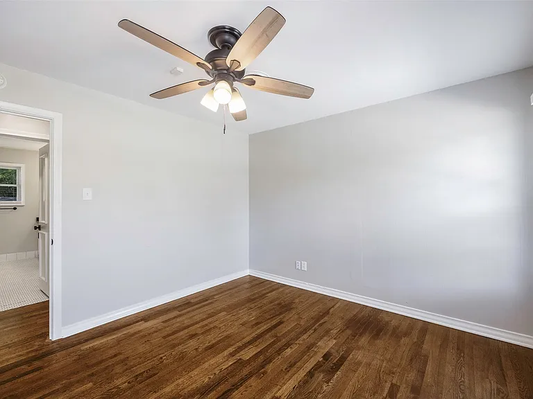 Spare room with dark wood-type flooring and ceiling fan