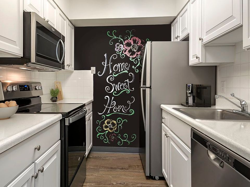 Renovated Package I kitchen with white cabinetry, laminate countertops, new stainless steel appliances, chalkboard accent wall, and hard surface flooring