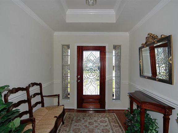 The entry features a wood and glass front door, trey ceiling, crown molding and wood floors.