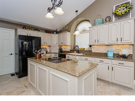 Updated kitchen with quartz counter tops, tile back splash, double oven, center island, electric cook top, crown molding on the 