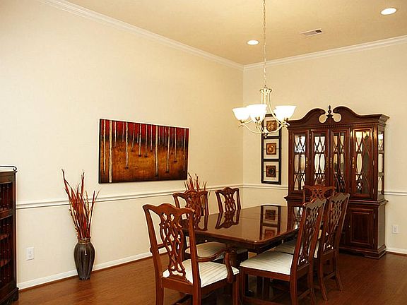 Formal Dining Room with wood flooring, crown molding & chair railing.