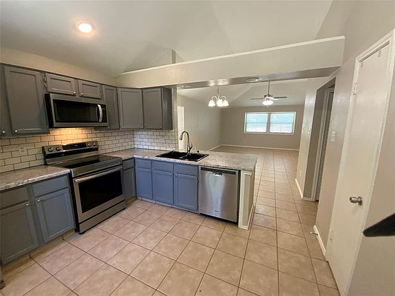 Kitchen featuring gray cabinetry, stainless steel appliances, a subway tile backsplash, and light-toned countertops