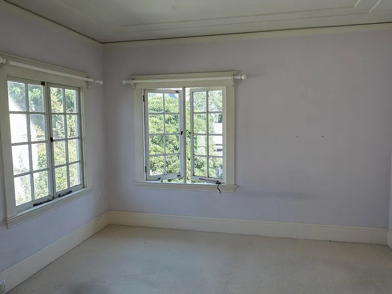 A large bedroom with excellent light and view of backyard.