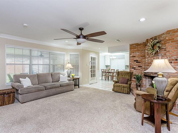 The large family room has crown molding, white blinds, recessed lights, and neutral paint!