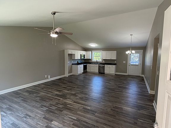 Front door looking into living area and kitchen dining area. Vaulted ceiling.