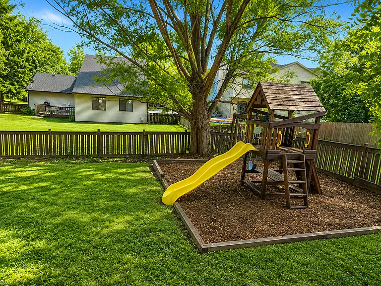 Backyard - 
The generous backyard provides the perfect blend of recreation and relaxation, featuring a large lawn, mature trees for natural shade, and a children's play area that makes outdoor living both fun and functional.