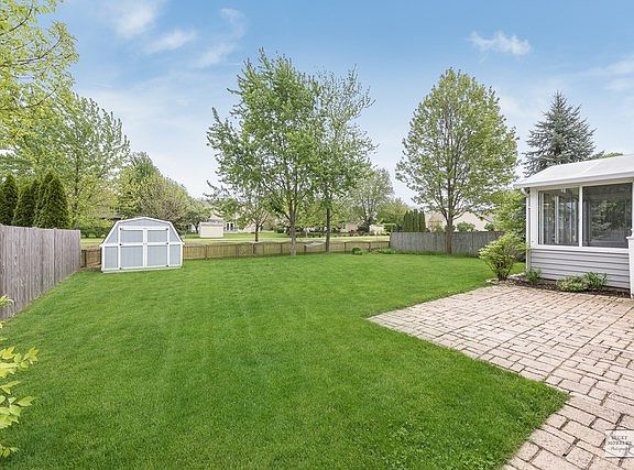 FENCED YARD WITH SHED, MATURE GARDENS & STONE PATIO.