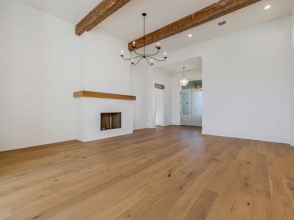Living room with exposed beams, brick fireplace, and views into the foyer
