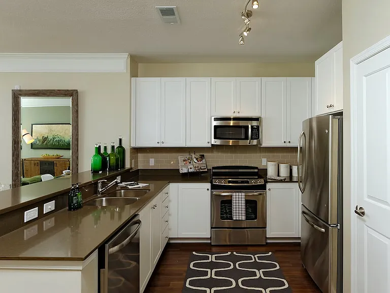Kitchen with quartz stone countertop, white cabinetry, tile backsplash, stainless steel appliances and hard surface flooring