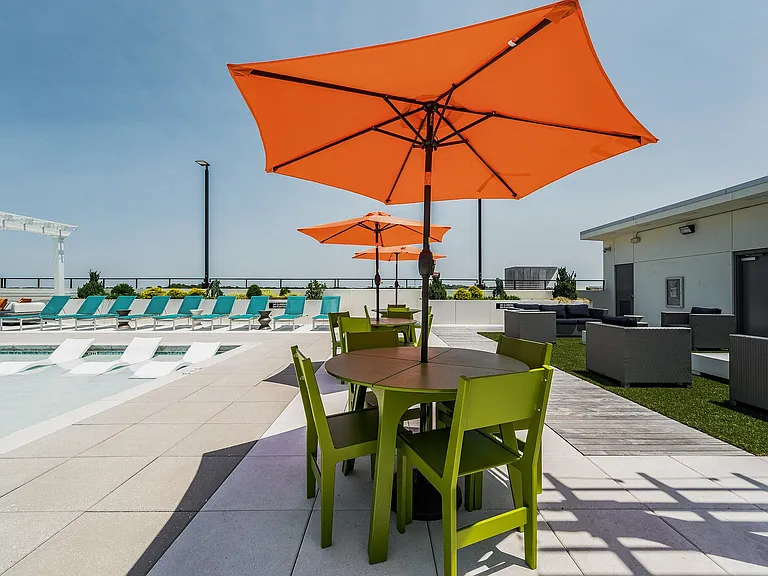 Table With Chairs and Umbrella On Rooftop Pool Deck