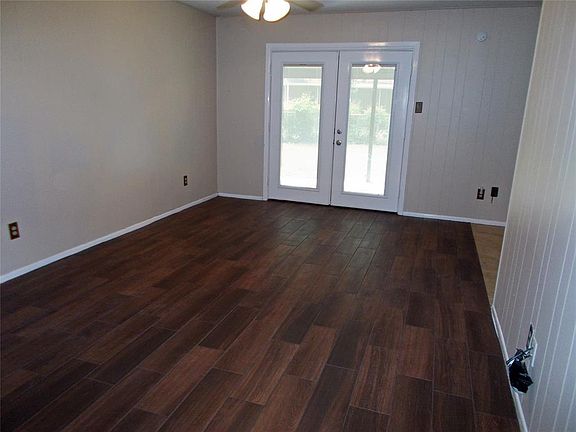 Comfortable family room has wood-look tile, french doors to the covered patio, CF, painted paneling, soft neutral colors