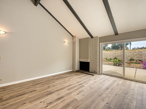 Living room with cozy fireplace, windows galore and enhanced by vaulted beam ceiling.