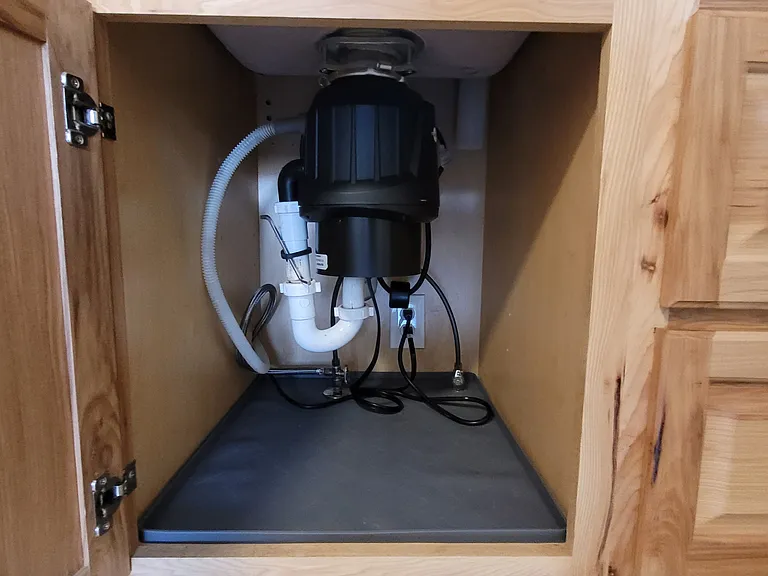 Stainless steel disposal and rubber mats inside kitchen and bath cabinets
