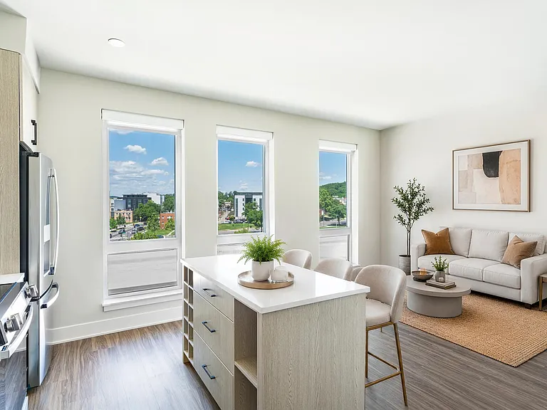 Open kitchen and living area with a central island and tall windows that bring daylight across the space and connect indoor areas seamlessly.