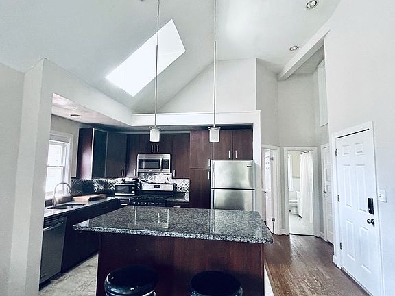 Kitchen. Island with marble counter. Vaulted ceilings with skylight.