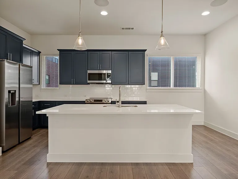 Kitchen view with beautiful island that seats four with elegant pendant lighting. Refrigerator, freezer, microwave, range, oven, and dishwasher are like brand new!