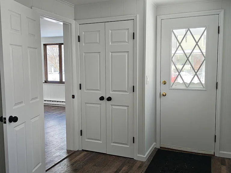 Entryway with double closet, entrance to living room.