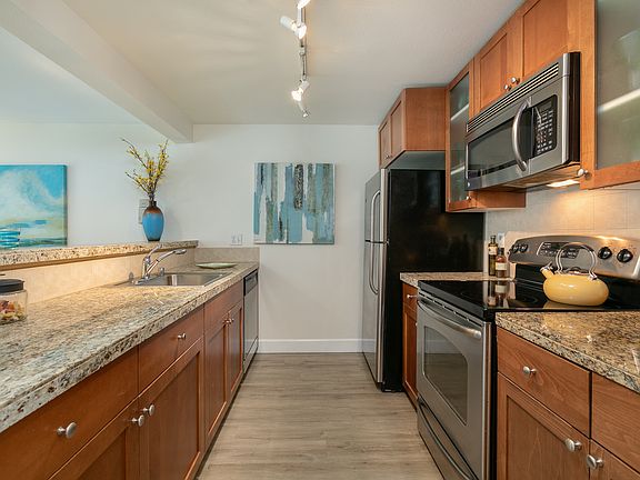 Bright kitchen with granite surfaces and stainless steel appliances.