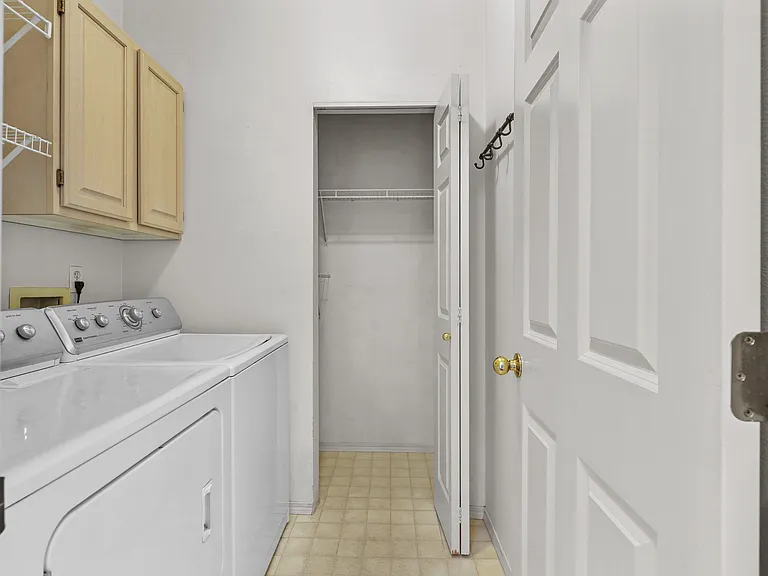 Laundry room showing full sized washer and dryer. Big storage area.