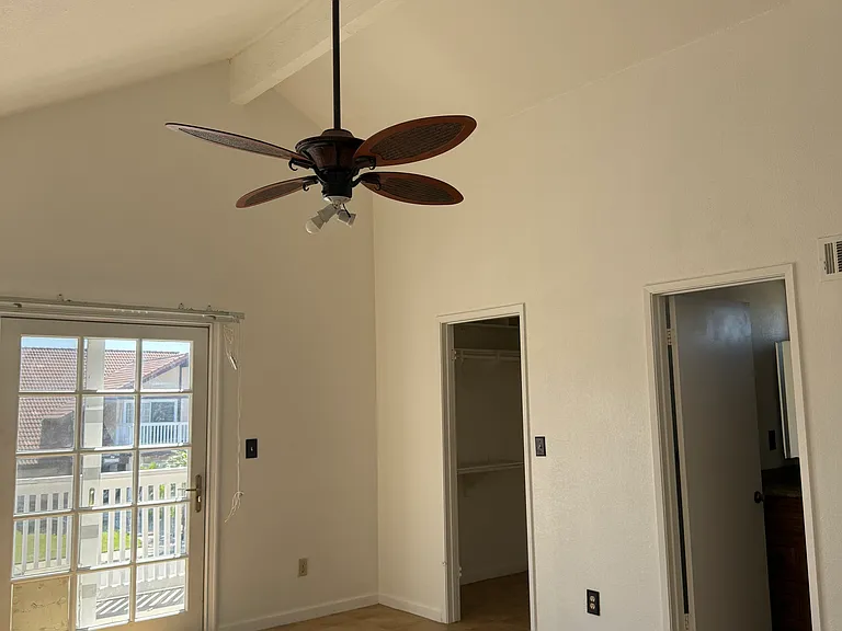 Primary bedroom has vaulted ceiling and balcony