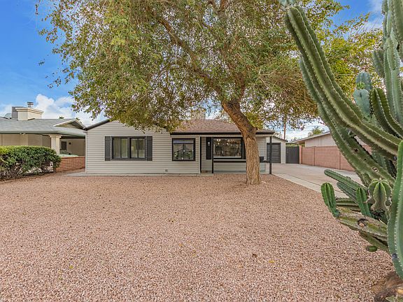 House sits off the street with a large shaded driveway and native landscaping