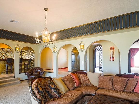 Upon entering the home, there's a gallery with arches leading into the huge living room. Plenty of room for lounging, entertaining and hanging out. The bar is visible on the left, the guest bathroom is through the door with the lattice work, and the red c