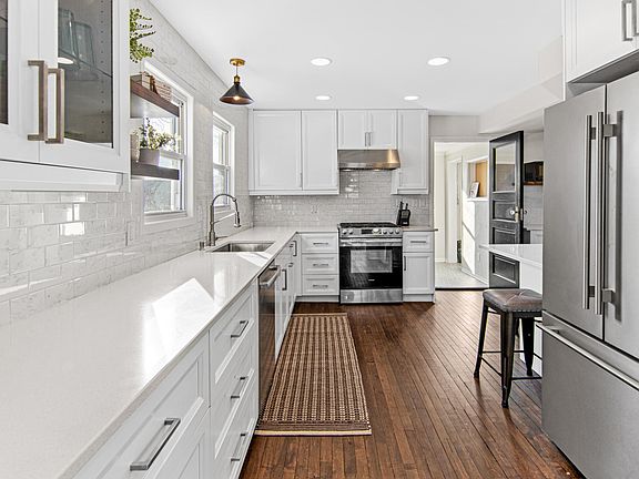 Beautifully remodeled kitchen with tiled backsplash up to the ceiling, quartz countertops, and new appliances