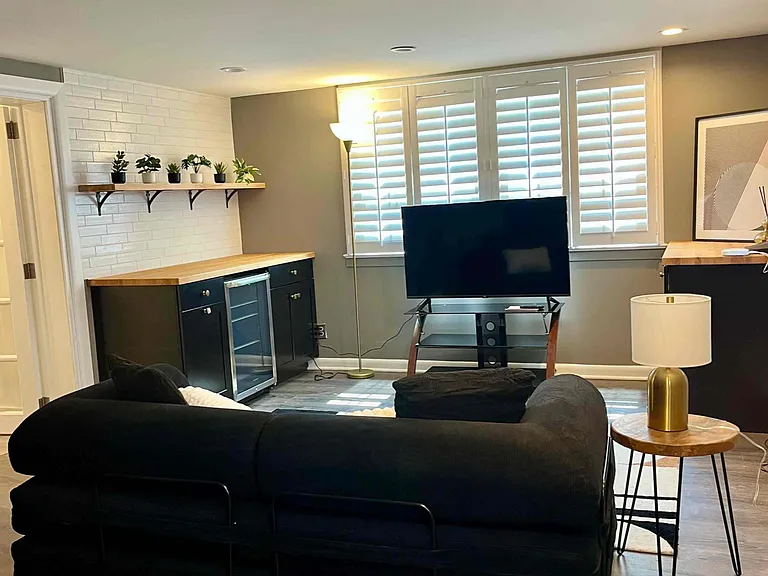 Studio suite in basement with fold-out futon, tv, and beverage fridge.