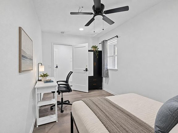 Private bedroom with a furnished work desk, ceiling fan, and window with curtains, plus a wardrobe for convenient storage.