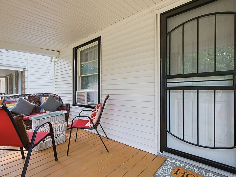 Covered front porch with seating area and outdoor tablean inviting spot for relaxing or enjoying fresh air at home.