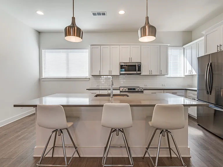 Kitchen with bar and pendant lights. Mounted microwave and full range and oven. Frigerator and freezer.