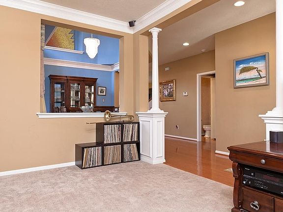 The living room also has decorative columns and a view of the dining room.